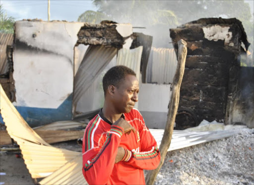 HORROR: A resident of Mpeketoni stands next to a house burnt by gunmen who killed 48 people on June 15.