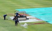 Ground staff workers are seen as they try to sweep water on the pitch after play was delayed due to rain. 