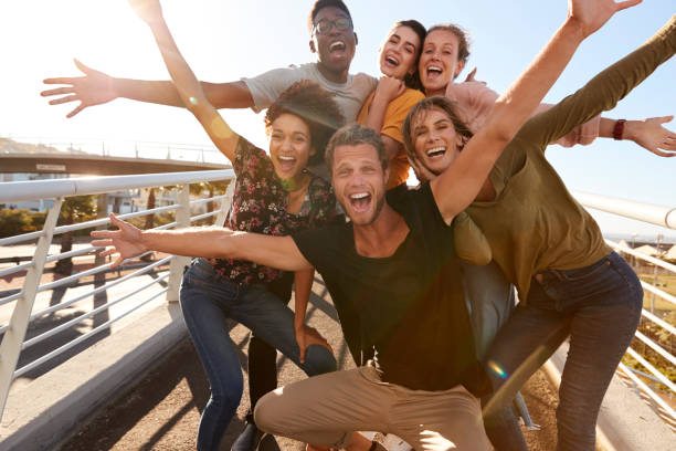 Young Friends Posing Like an Excited Gang Ready to Party With Arms in the Air & Smiling Faces