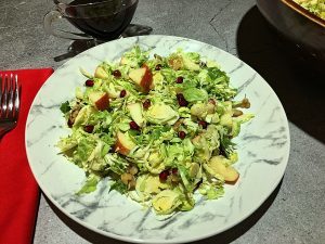 A delicious & healthy Brussels Sprouts Salad with onions, pomegranate seeds, apple, walnuts and cheese.