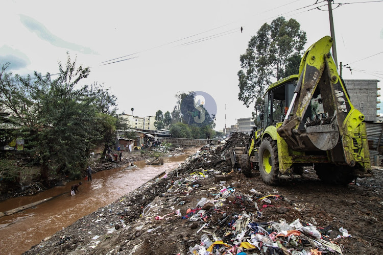 A bulldozer collects garbage piled at Nairobi River near Ngara Nyayo market
