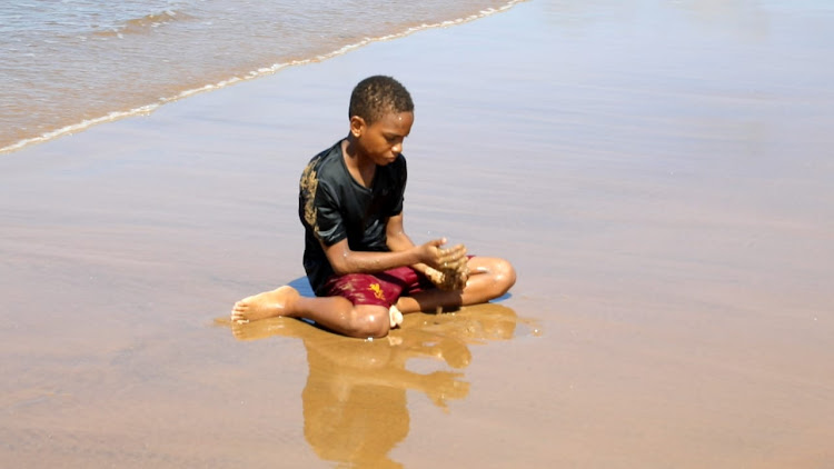 A boy plays with sand in the beaches of Malindi during the Easter holidays