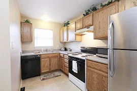 Kitchen with oak cabinets, neutral countertops, appliances of varying color, and a window above the sink