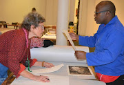 Employers at the Tatum Art Gallery pour over some of the artwork damaged during an act of sabotage last week.