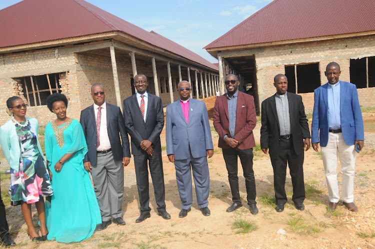 The Bishop takes a group picture with the Uganda Baati team infront of the North Ankole Mission Hospital under construction