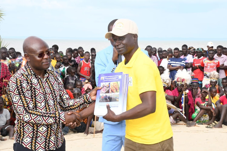 Turkana Deputy Governor John Erus hands over copies of fishing guidelines to a fisheries officer at Eliye Springsin Kangatotha ward