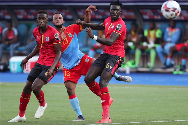 DR Congo's Meshack Elia shopots under pressure from two Ugandan opponents during their Cup of nations group stage match