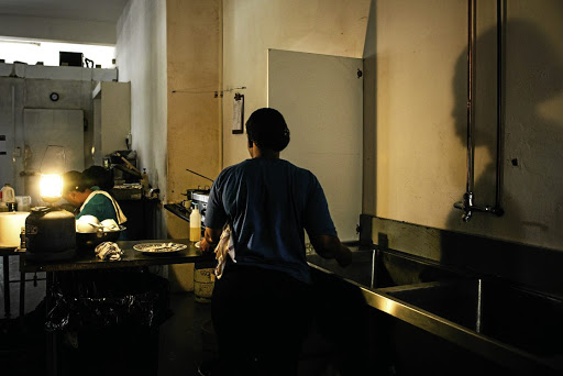 Workers in a cafe use an emergency gas-powered lamp to illuminate the kitchen during a power outage.