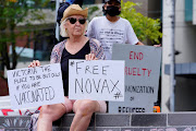 A protester holds signs outside the Park Hotel, where Serbian tennis player Novak Djokovic is believed to be held, in Melbourne, Australia, on January 6 2022.