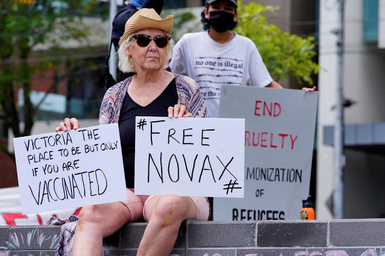 A protester holds signs outside the Park Hotel, where Serbian tennis player Novak Djokovic is believed to be held, in Melbourne, Australia, on January 6 2022.