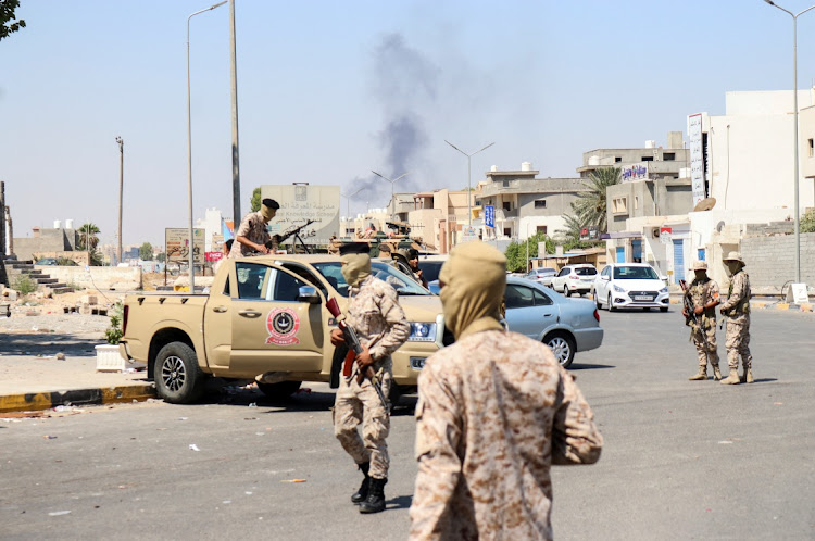 Members of the Libyan armed unit, 444 Brigade, backing the Government of National Unity (GNU) and its prime minister Abdulhamid al-Dbeibah, set up a checkpoint as smoke rises in the background in Ain Zara area in Tripoli, Libya, July 22 2022. Picture: REUTERS/HAZEM AHMED