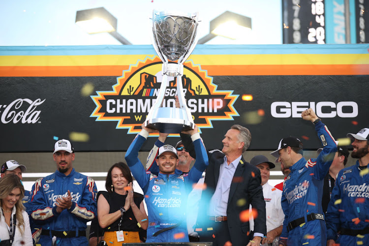 Kyle Larson, driver of the No 5 HendrickCars.com Chevrolet, is presented the Bill France 2021 NASCAR Cup Series Championship trophy by NASCAR president Steve Phelps after winning the NASCAR Cup Series Championship at Phoenix Raceway on November 7 2021 in Avondale, Arizona.