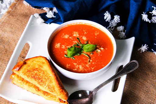 A bowl of Spicy Crock Pot Tomato Bisque with a grilled cheese sandwich.