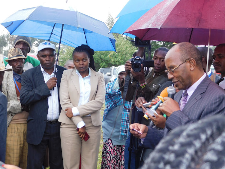 Officer in charge of NHIF in Nyandarua Nina Muthamia (in cream suit) and Nyandarua Governor Francis Kimemia issue NHIF cards to Murungaru residents on Wednesday