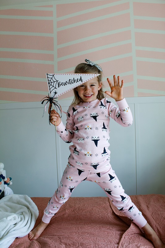 Little girl in Halloween pajamas holding a Halloween Flag