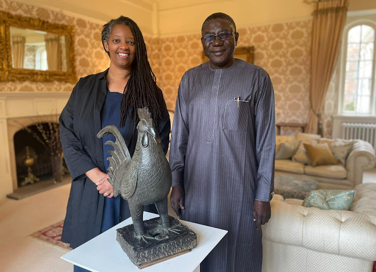 This undated handout photograph received from the University of Cambridge on October 27, 2021, shows Master of Jesus College Sonita Alleyne (L) and Director-General of the National Commission for Museums and Monuments of Nigeria, Professor Abba Isa Tijani with the elaborately carved cockerel, known as "Okukor", during a handing over ceremony at Jesus College, University of Cambridge, Cambridge on October 27, 2021.