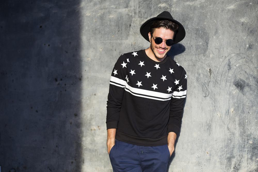 Young man posing with a trendy outfit against a urban background