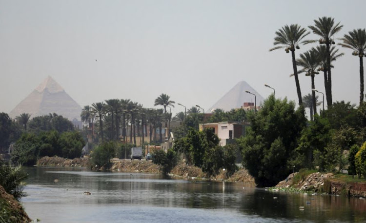 The Great Giza pyramids are seen behind a canal which flows into the River Nile on the outskirts of Cairo, Egypt on August 1, 2017.