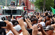 Mourners watch and take photos as the coffin of Brazilian football legend Pelé passes during the funeral procession through the streets of Santos, Brazil as it approaches the football legend's final resting place at Memorial Necrópole Ecumênica cemetery on January 3 2023.