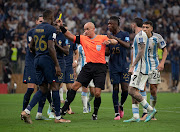 Referee Szymon Marciniak shows a yellow card to Marcus Thuram of France while Eduardo Camavinga, Adrien Rabiot, Rodrigo De Paul and Nahuel Molina of Argentina protest during the 2022 Fifa World Cup final at Lusail Stadium in Lusail City, Qatar on December 18 2022.