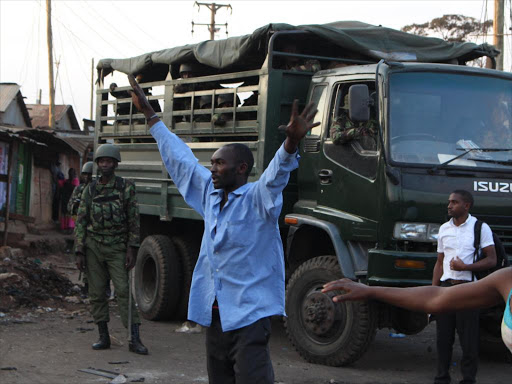 A police officer looks on as Nasa supporters in Kawangware 56 demonstrate in support of Presidential candidate Raila Odinga claiming he had won the election on the evening of Thursday, August 11. /COLLINS KWEYU