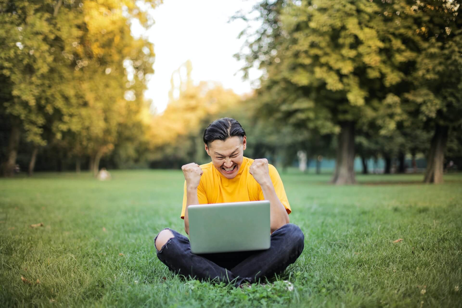 Student sitting outside on the lawn with a laptop