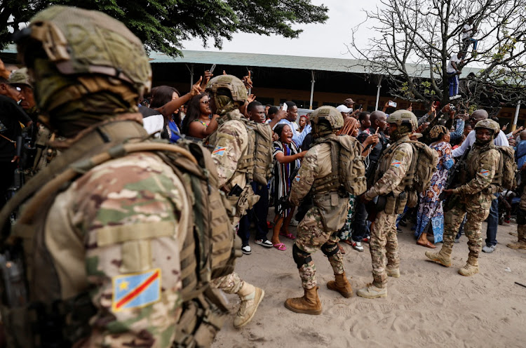 Republican guard form a security cordon, as supporters of DRC's President Felix Tshisekedi cheer for him, after he cast his vote at a polling station, during the presidential election, in Kinshasa.