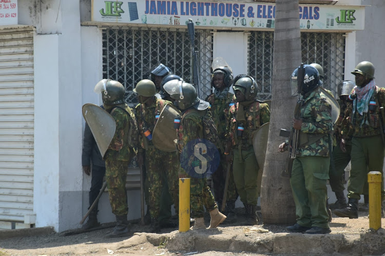 Police officers take cover before invading protesters at Jua Kali on July 19, 2023.