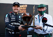 Pole position qualifier Valtteri Bottas is presented with the Fangio Award to commemorate 70 years since Juan Manuel Fangio's first F1 World Drivers Championship win, by Sir Jackie Stewart in parc ferme during qualifying ahead of the F1 Grand Prix of Mexico at Autodromo Hermanos Rodriguez on November 06, 2021 in Mexico City, Mexico.