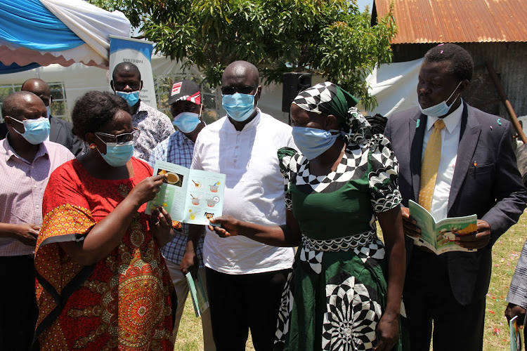 Agriculture CAS Jebii Kilimo shows a recipes booklet to farmer Joyce Auma during the handover of pond construction materials at the Fisheries offices in Homa Bay town on September 17, 2020.