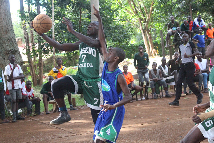 Brian Beast of Maseno School goes for a basket as Marlic Mukhtar of Ambira attempts to block him in the boys' finals during Maseno-Amadi tournament.