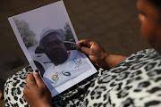 Neo Molobela holding a picture of her murdered brother, Simon Sepaka.