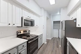 Kitchen with stainless steel appliances, light upper and neutral lower cabinets with black handles