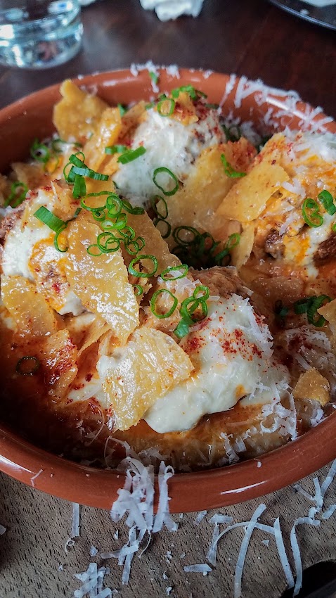 Bar Casa Vale Brunch Chicken Meatball Cazuela with bomba rice grits, tomato, cilantro, and fried egg and topped with chicken skin