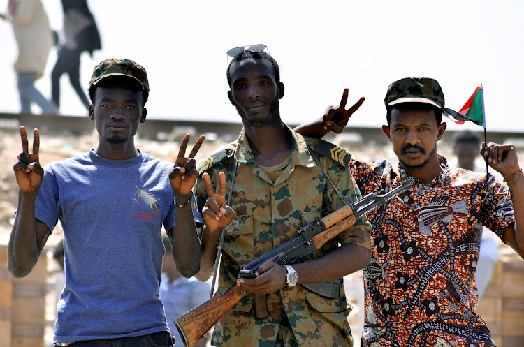 A Sudanese military officer and demonstrators gesture in celebration after Defence Minister Awad Ibn Auf stepped down as head of the country's transitional ruling military council, as protesters demanded quicker political change, near the Defence Ministry in Khartoum, Sudan April 13, 2019.