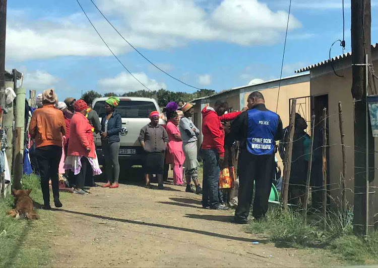 Community members, police and crime scene investigators at the home of the child who was run over by a minibus this morning