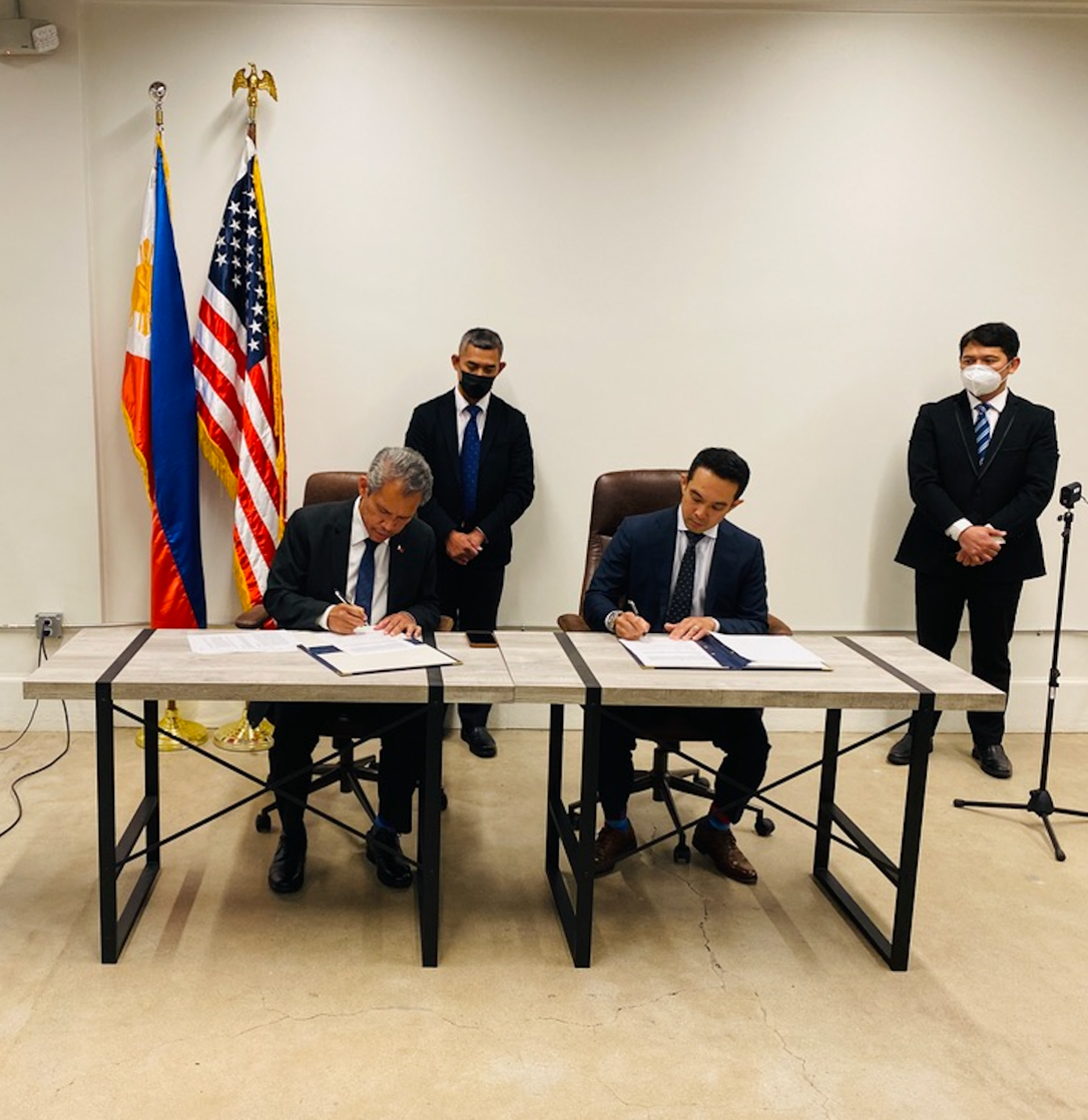 A group of men in suits sitting at a table with flags

Description automatically generated with low confidence