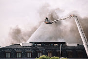 Smoke billows into the air on Monday after a fire at the parliament building reignited, seemingly by winds that were beginning to pick up.