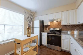 Modern kitchen with white cabinetry, stainless steel appliances, a moveable island table, and tiled backsplash.