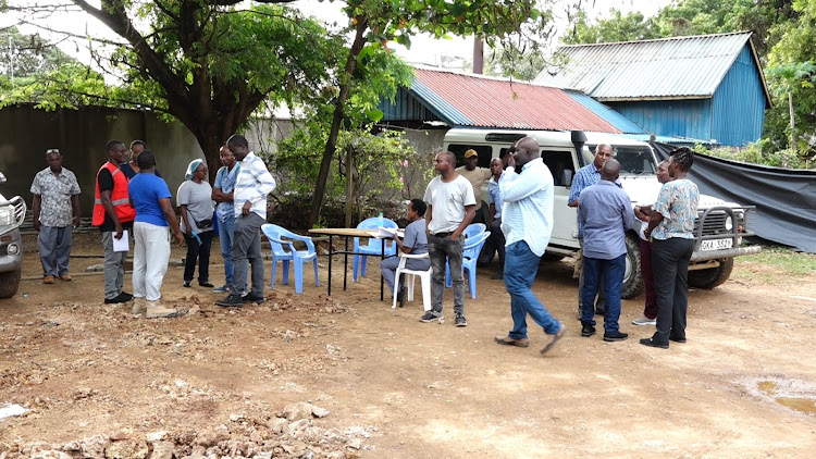 The experts doing the postmoterm together with journalists and Kenya Red Cross officials outside the Malindi mortuary after completing day two of the posmoterm of 30 bodies .