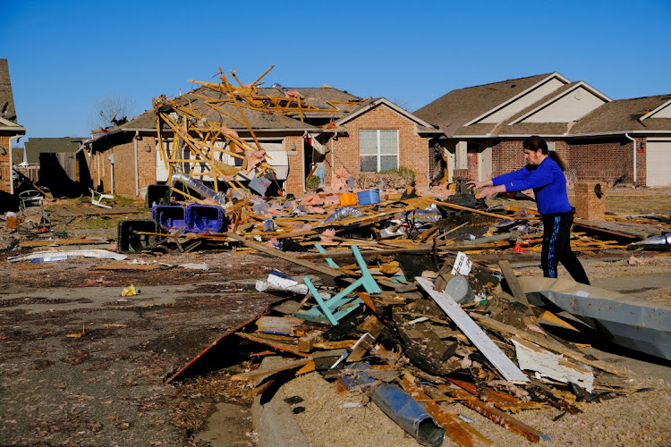 A man tosses debris into a pile as he cleans up damage caused by tornadoes that hit overnight in Norman, Oklahoma, US, February 27, 2023.