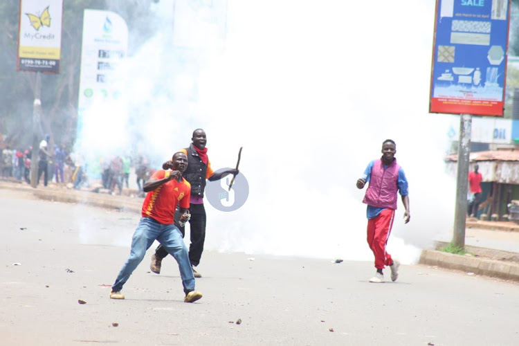 Protesters react after being lobbed with teargas canister at Kisumu bus-park on March 27, 2023.