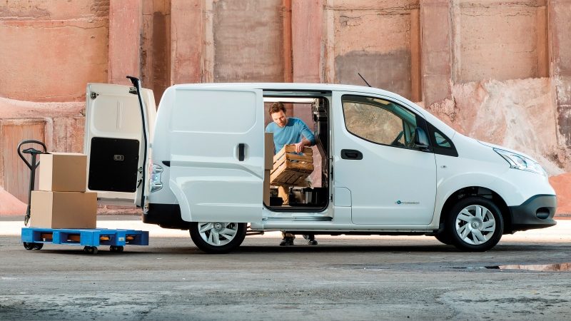 Profilo del nuovo Nissan e-NV200 con porte aperte e uomo che carica il veicolo