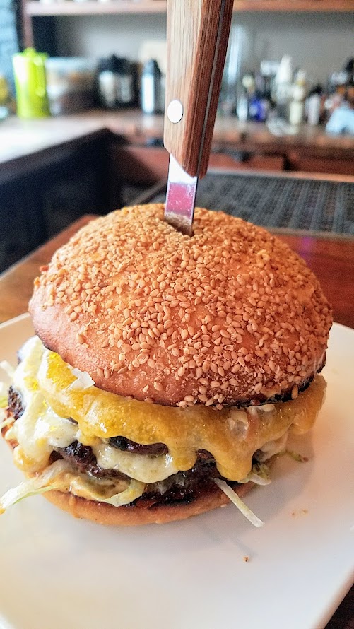 Superbite Happy Hour item Double Stack Cheeseburger with grilled ground beef and shitake, cheddar and fontina cheeses on the two patties, fancy sauce, dill pickle, onion, sesame seed bun