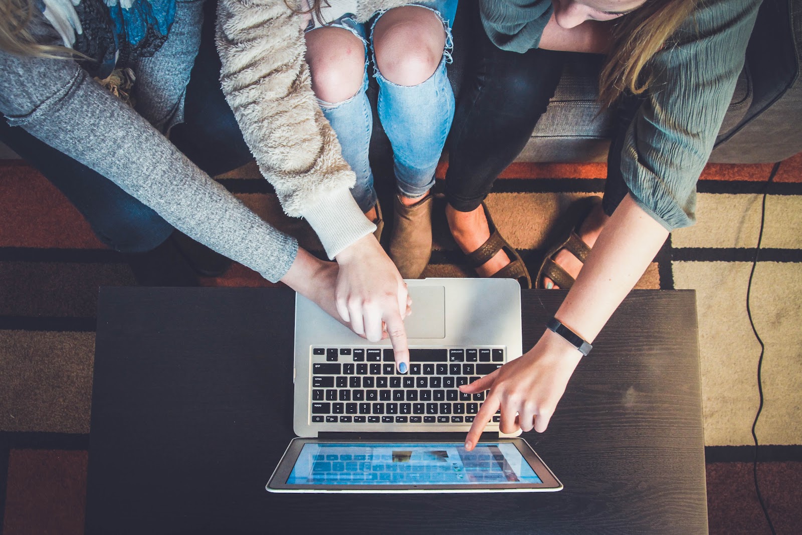 An image of a computer with three people huddled around it, pointing at the screen.