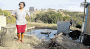  Mandisa Buzani stands in front of the overflowing sewage pump inside her yard in Cambridge location. 