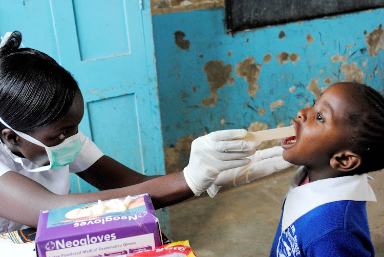 Nurse Hawa Kwamboka screens a Standard 1 pupil at Kilimani Primary School on World Oral Health Day.