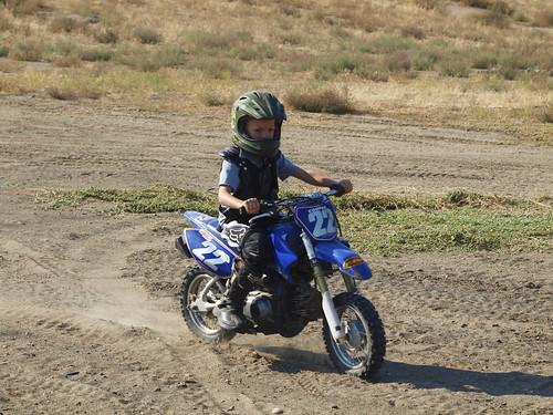 a child driving a dirt bike on a a dirt path