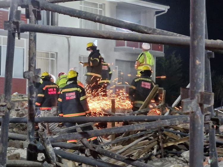 Rescue workers at the collapsed multi-storey building under construction in Victoria Street, George. Two workers were confirmed dead and 53 remained trapped on Monday night.