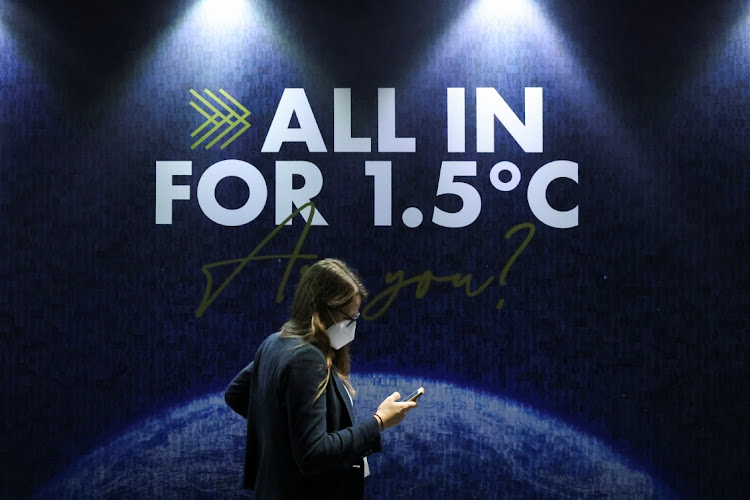 A delegate walks past a sign during the UN Climate Change Conference (COP26) in Glasgow, Scotland, on November 11 2021. Picture: REUTERS/YVES HERMAN